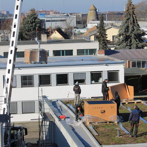 Die ersten Solarplatten werden installiert. Mit Hilfe eines Krans wurden die Paletten auf das Dach gehoben.