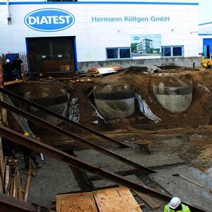 Right at the beginning of January the excavations works continued. The rain water cisterns and the oil separator can be seen again for a short time. The I-Beams support the wall of the neighboring site. First parts of the bottom plate are casted,…