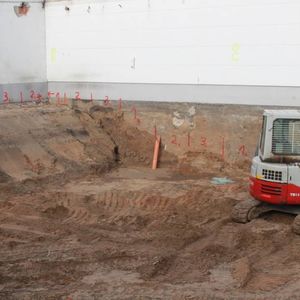 The bottom plate of the new building will be a lot deeper in the earth as the one of the old and bordering building. To prevent the old building from collapsing the excavation works have to be done in a certain order – therefore the red numbers on the wall…