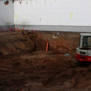 The bottom plate of the new building will be a lot deeper in the earth as the one of the old and bordering building. To prevent the old building from collapsing the excavation works have to be done in a certain order – therefore the red numbers on the wall…
